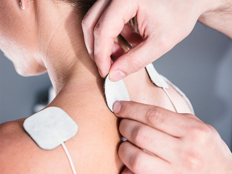 Woman getting electric stim pads put on neck